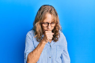 Orta yaşlı, sıradan kıyafetler ve gözlük takan sarışın bir kadın kendini iyi hissetmiyor ve soğuk algınlığı veya bronşitin belirtisi olarak öksürüyor. sağlık hizmeti kavramı. 