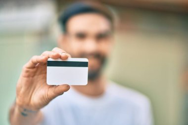 Genç İspanyol adam gülümsüyor, şehirde kredi kartı tutarken mutlu..