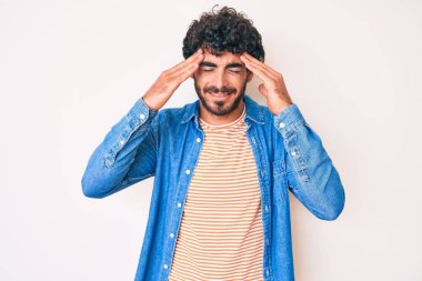 Kıvırcık saçlı yakışıklı genç adam ve ayı stresten dolayı başı ağrıyan sıradan bir kot ceket giyiyor. migren ağrısı. 