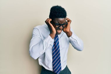 Yakışıklı, gözlüklü, iş gömleği giyen, kravatlı, kulaklarını parmaklarıyla kapatan, rahatsız edici ifadeli, yüksek sesli müzik sesi çıkaran siyahi adam. sağır kavramı. 