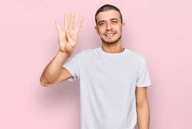İspanyol asıllı beyaz tişört giymiş dört numarayı gösterip işaret eden kendinden emin ve mutlu gülümseyen genç adam.. 