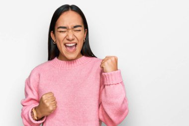 Sıradan bir kazak giyen genç Asyalı kadın kolları havada ve gözleri kapalı bir şekilde başarıyı kutluyor ve şaşırıyor. Kazanan konsept. 