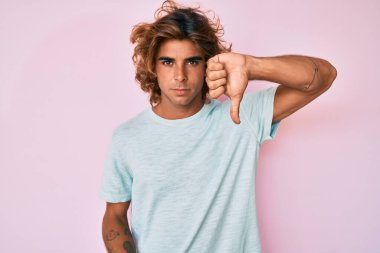 Gündelik kıyafetler giyen genç İspanyol adam mutsuz görünüyor ve reddediliyor ve olumsuz bir hareket yapıyor. kötü ifade. 