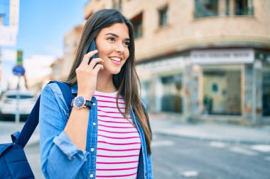 Genç İspanyol öğrenci gülümseyerek şehirde akıllı telefondan konuşmaktan mutlu oluyor..