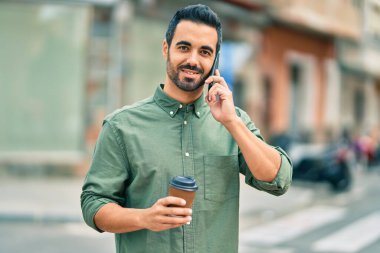 Genç İspanyol adam akıllı telefondan konuşuyor. Şehirde kahve içiyor..