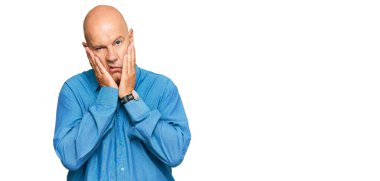 Orta yaşlı kel bir adam günlük kıyafetler giyiyor. Yorgun eller, yüzünü kapatıyor. Depresyon ve üzüntü yaşıyor. 