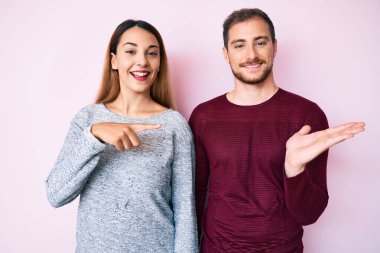 Gündelik giysiler giyen güzel çift kameraya hayret ediyor ve gülümsüyor. Elleriyle ve parmaklarıyla gösteriyorlar.. 