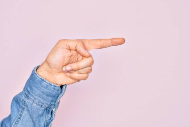 İzole edilmiş pembe arka plan üzerinde parmaklarını gösteren beyaz bir gencin eli işaret parmağıyla kenarı işaret ediyor ve bir seçim yapıyor.