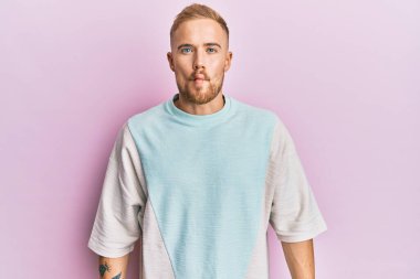 Günlük kıyafetler giyen genç beyaz bir adam dudaklarıyla balık suratı yapıyor, çılgınca ve komik bir jest. Komik ifade. 