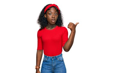 Gündelik giysiler giyen güzel Afrikalı genç bir kadın elleri yana dönük, ağzı açık hayret dolu bir ifadeyle şaşırdı.. 