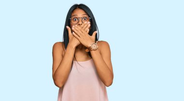 Sıradan kıyafetler ve gözlük takan Afro-Amerikalı genç bir kadın yanlışlıkla ağızlarını kapatarak şok geçirdi. gizli kavram. 