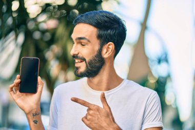 Genç İspanyol adam gülümsüyor. Mutlu bir şekilde parmakla gösterip, akıllı telefonuyla şehre işaret ediyor..