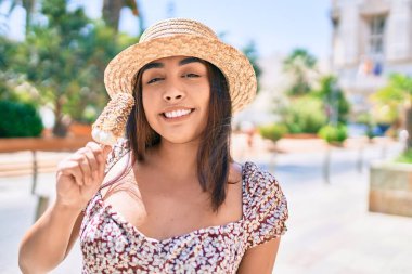 Genç Latin kadın tatilde gülümsüyor mutlu bir şekilde çikolatalı dondurma yiyor ve caddede yürüyor..