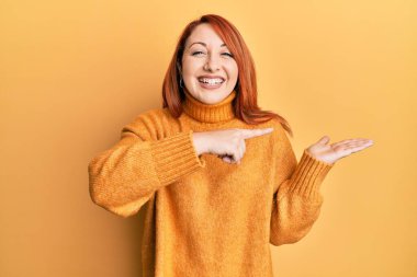 Güzel kızıl saçlı kadın, parmaklarıyla boşluğu işaret ederek avucunun içinde gülümsüyor ve kahkahalarla gülüyor.. 