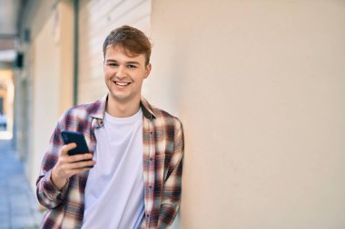 Beyaz adam şehirde akıllı telefon kullanarak mutlu bir şekilde gülümsüyor..