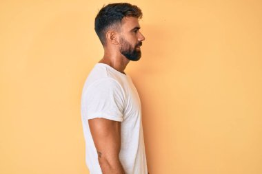 Latin kökenli genç adam rahat bir görünüm takınıyor, rahat bir görünüm takınıyor, kendine güvenen bir gülümsemeyle.. 