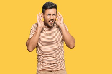 Gündelik kıyafetler giyen yakışıklı İspanyol adam iki elini de kulak hareketlerini duymaya çalışıyor, dedikoduya meraklı. İşitme sorunu, sağır 
