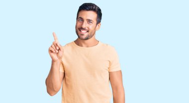 Gündelik kıyafetler giyen genç İspanyol bir numarayı gösterip işaret ederken kendinden emin ve mutlu bir şekilde gülümsüyor.. 