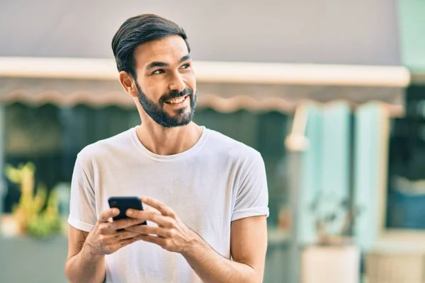 Joven Hombre Hispano Sonriendo Feliz Usando Smartphone Ciudad —  Fotos de Stock