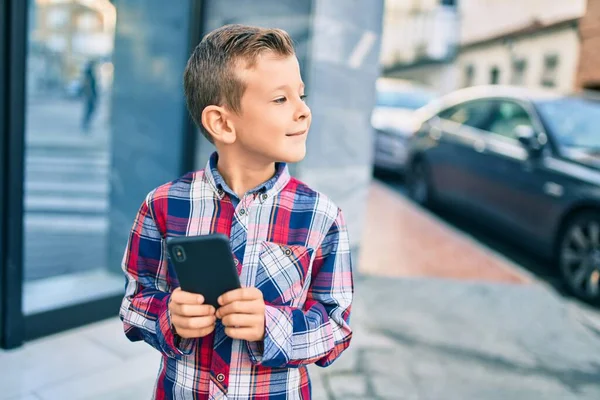 Beyaz Çocuk Şehirde Akıllı Telefon Kullanarak Mutlu Bir Şekilde Gülümsüyor — Stok fotoğraf