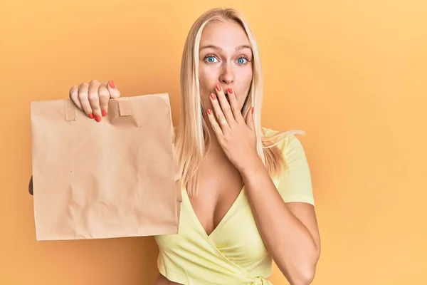 Young Blonde Girl Holding Take Away Paper Bag Covering Mouth — Stock Fotó
