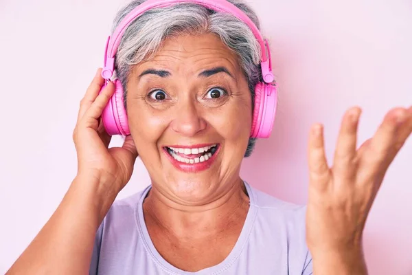 Mulher Hispânica Sênior Ouvindo Música Usando Fones Ouvido Celebrando Vitória — Fotografia de Stock