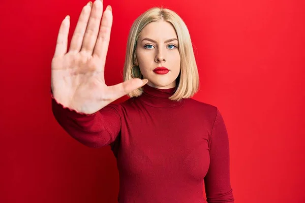Young blonde woman wearing casual clothes doing stop sing with palm of the hand. warning expression with negative and serious gesture on the face.