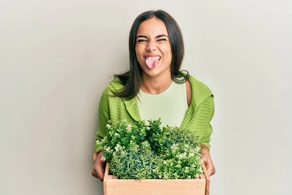 Young Brunette Woman Holding Wooden Plant Pot Sticking Tongue Out —  Fotos de Stock