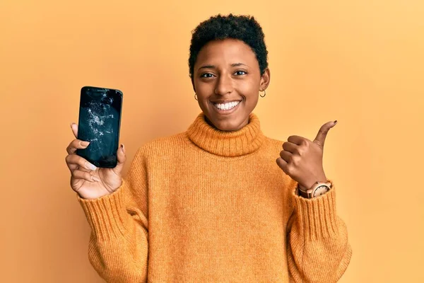 Młoda Afrykańska Dziewczyna Trzyma Złamany Smartfon Pokazując Pęknięty Ekran Uśmiechnięty — Zdjęcie stockowe