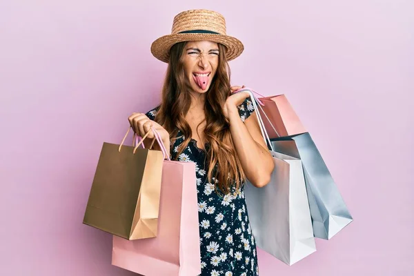 若いですブルネット女性保持ショッピングバッグステッキング舌アウト幸せとともに面白い式 — ストック写真