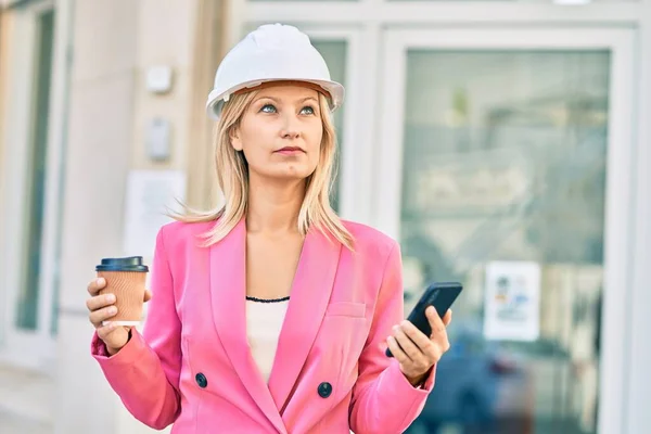 若い白人建築家の女性が市内でスマートフォンやコーヒーを使って — ストック写真
