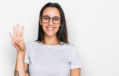 Gündelik beyaz tişört giyen genç İspanyol kadın dört numarayı gösterip işaret ederken kendinden emin ve mutlu bir şekilde gülümsüyor.. 