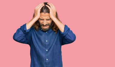 Uzun saçlı, sakallı, günlük kıyafetler giyen, baş ağrısı çeken, çaresiz ve stresli bir adam. Çünkü acı ve migren ağrısı var. Eller başının üstünde.. 