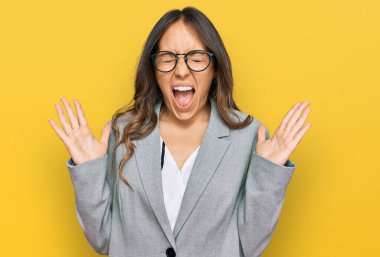 İş kıyafetleri giymiş genç esmer kadın başarı için deli ve çılgınlığı kutluyor kollarını kaldırmış ve gözlerini kapatmış heyecanla bağırıyor. Kazanan konsept 