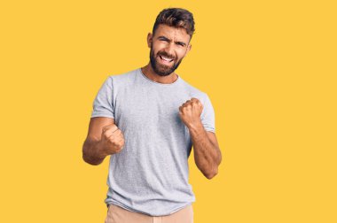 Gündelik giysiler giyen genç İspanyol adam kolları havada ve gözleri kapalı bir şekilde başarının şaşkınlığını ve şaşkınlığını yaşıyor. Kazanan konsept. 