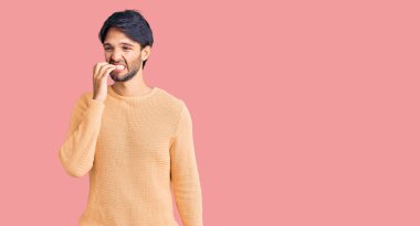 Yakışıklı, sıradan süveter giyen, gergin ve gergin görünen, elleri ağızdan tırnak yiyen bir İspanyol. anksiyete. 