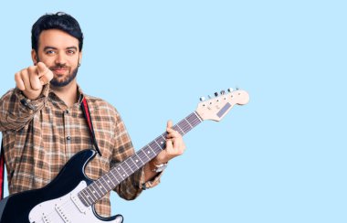 Elektro gitar çalan genç İspanyol adam kamerayı işaret ediyor ve sen kendine güvenen ciddi bir hareket yapıyorsun. 