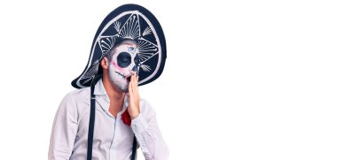 Arka planda ölü kostümü giymiş bir adam ağzıyla esnemekten sıkılmış. Huzursuz ve uykulu.. 