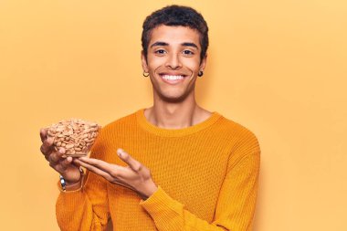 Fıstık tutan Afrikalı genç bir Amerikalı. Olumlu ve mutlu görünüyor. Kendine güvenen bir gülümsemeyle dişlerini gösteriyor. 