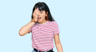 Latin asıllı genç bir kız günlük kıyafetler giyiyor. Yarı yüz, yarı göz, yarı ağız, yarı el esneme yorgunu. Yüzüm acıyor.. 