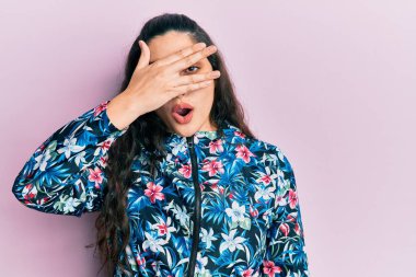 Güzel bir ortadoğulu kadın, sıradan bir çiçek ceketi giyiyor. Şoka giriyor, yüzünü ve gözlerini eliyle kapatıyor. Utanmış bir ifadeyle parmaklarından bakıyor.. 