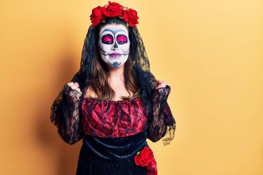 Sarı renkli ölü kostümünü giydiği gün kolları havada ve gözleri kapalı zaferi kutlarken heyecanlanan genç bir kadın. Kazanan konsept. 