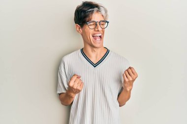 Gündelik kıyafetler ve gözlük takan genç İspanyol adam başarı için heyecanlanıyor kolları havada ve gözleri kapalı zaferi kutluyor. Kazanan konsept. 
