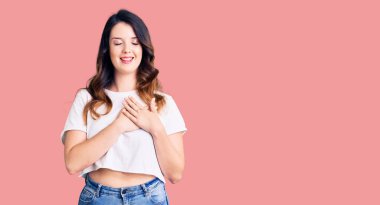 Güzel, genç, esmer, sıradan kıyafetler giyen, elleri göğsünde, gözleri kapalı ve yüzünde minnet dolu bir jest olan bir kadın. sağlık kavramı. 