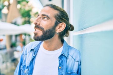 Orta Doğulu genç adam gülümsüyor. Mutlu bir şekilde şehrin duvarına yaslanıyor..