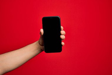 Kafkas genci elinde akıllı telefon var. İzole edilmiş kırmızı arkaplanda ekranı gösteriyor.
