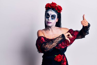 Meksika 'da ölü makyajı yapan genç bir kadın baş parmaklarını kaldırıyor, anlaşmazlık ve anlaşma ifadesi takınıyor. çılgın çatışma 