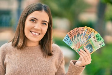 Genç İspanyol kadın gülümseyerek Avustralya dolarlarını şehirde tutuyor..