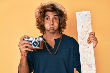 Klasik fotoğraf makinesi tutan genç bir İspanyol ve komik suratlı bir şehir haritası şişiren yanakları. Ağzı havayla şişer, havayı yakalar.. 