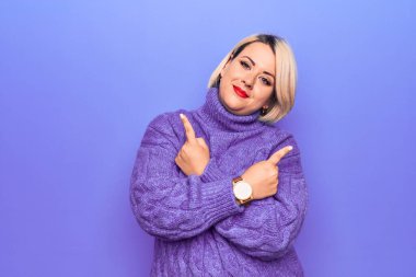 Güzel sarışın ve cüsseli bir kadın mor arka planda balıkçı yaka kazak giyiyor. Her iki tarafı da parmaklarıyla işaret ediyor. Farklı yönler farklı.